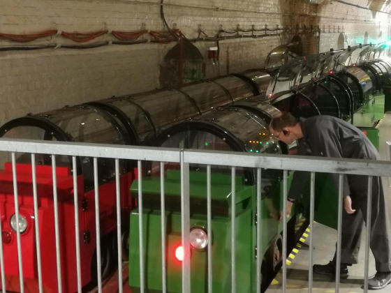 An engineer looking at some small railway carriages inside a tunnel